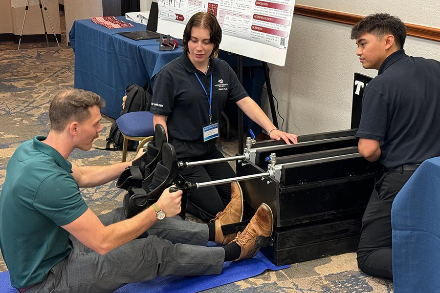 two kinesiology students help man use the exercise device