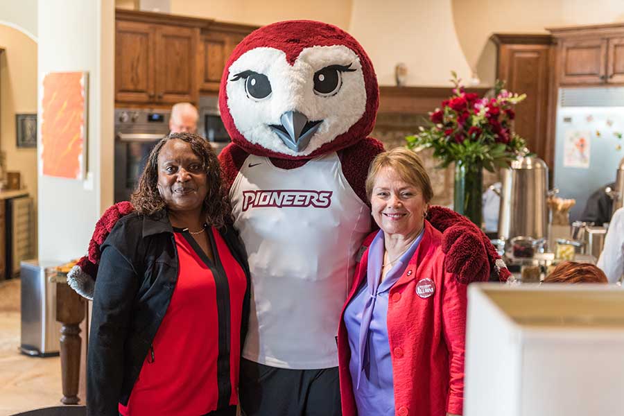 Oakley hugs two alumni during an event at Chancellor Feyten's house.