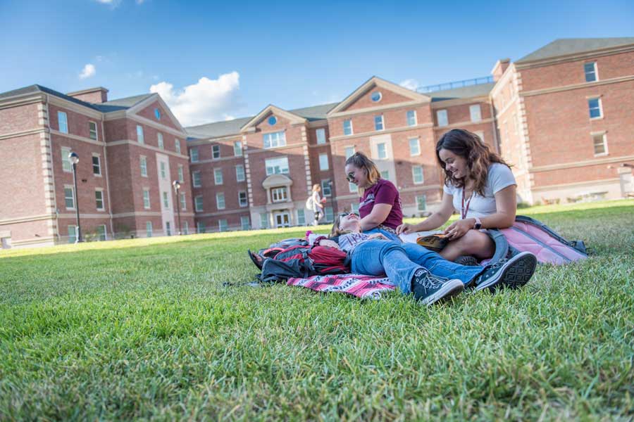 Students relax on the lawn outside the Parliament dorm building on TWU's Denton campus.