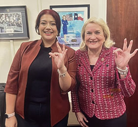 A student and congresswoman Sylvia Garcia pose in an office doing the TWU hand signal.