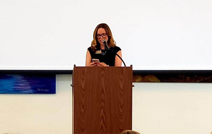 woman stands behind podium reading notes . 