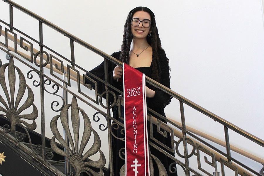 Emily Kraft stands on a stairwell with a maroons stole