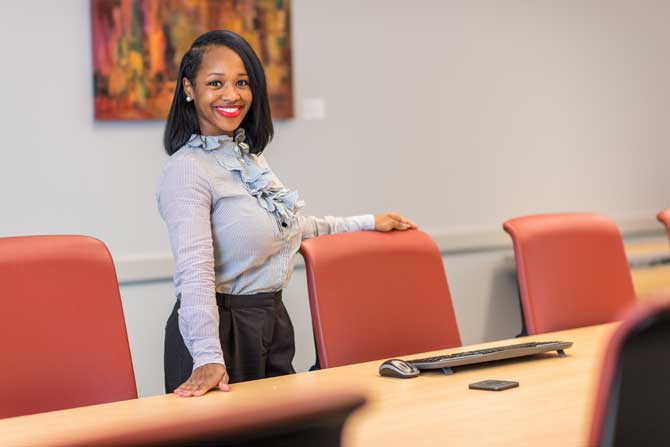 A woman in professional attire in an office setting.