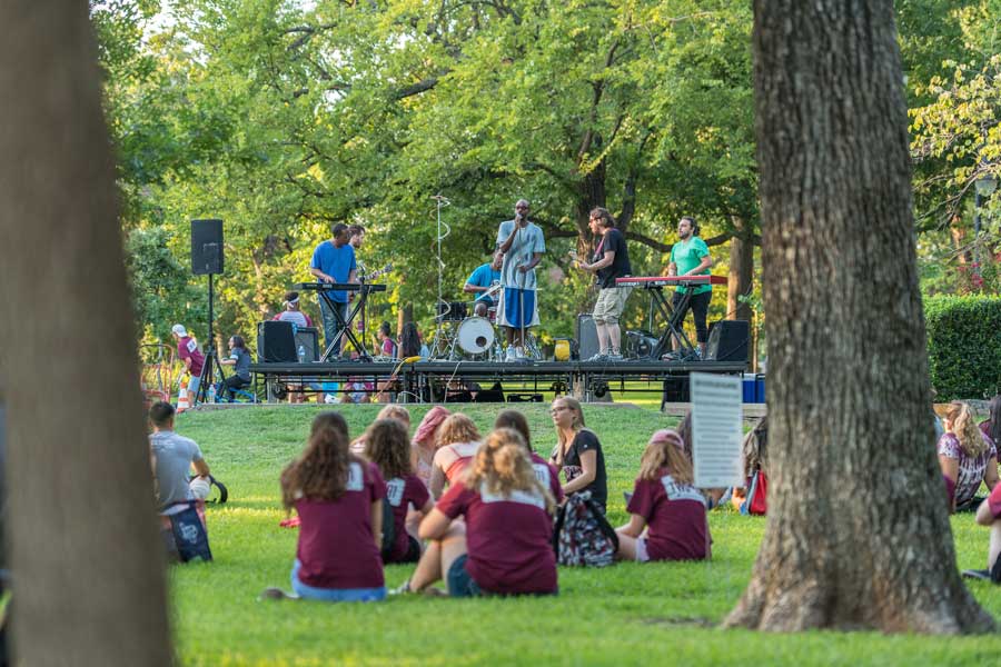 TWU students relax at the block party while a band performs.	