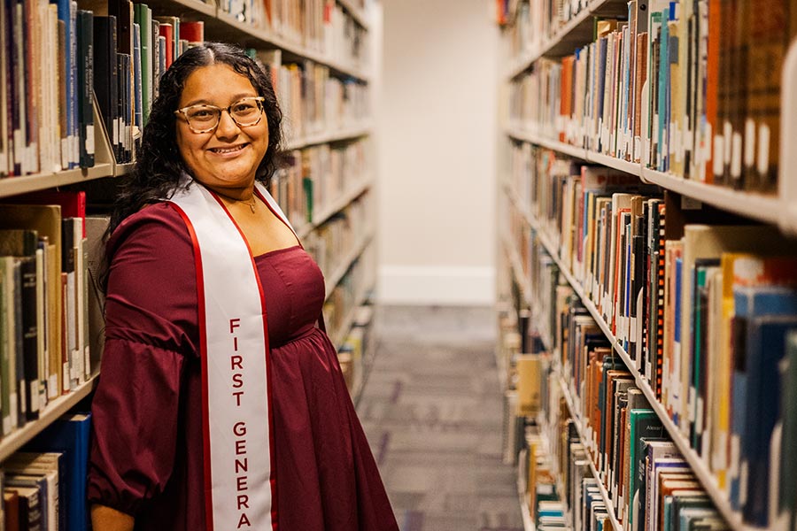 Magali Castillo Nicolas stands in the TWU library aisle