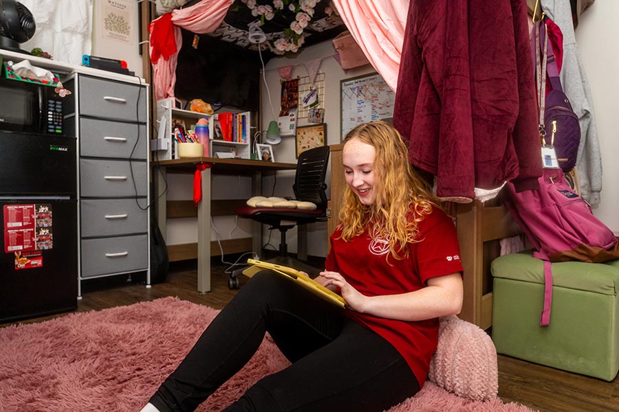 A TWU student studies on a fluffy area rug in her dorm