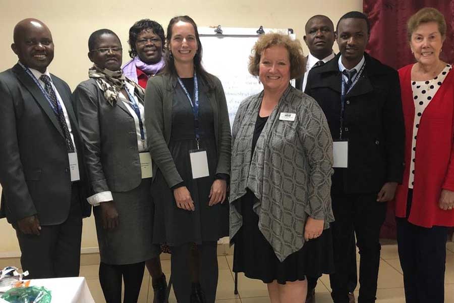 A group of people smile and pose in professional clothing.