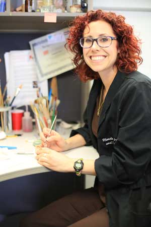 Colette Shrader sits at her desk and smiles.