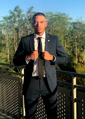 full-length photo of Theodore Fields in business suit on a bridge in front of trees