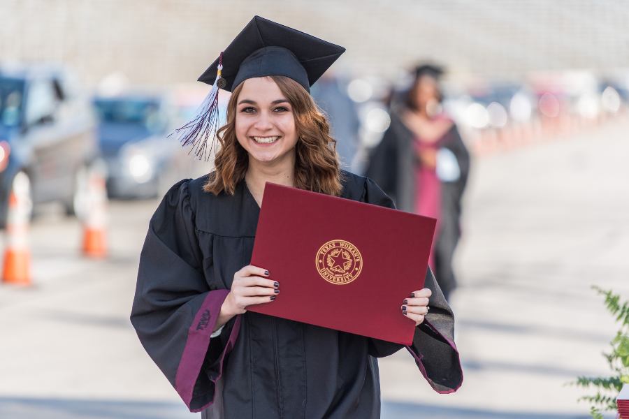 A young woman shows off her TWU diploma