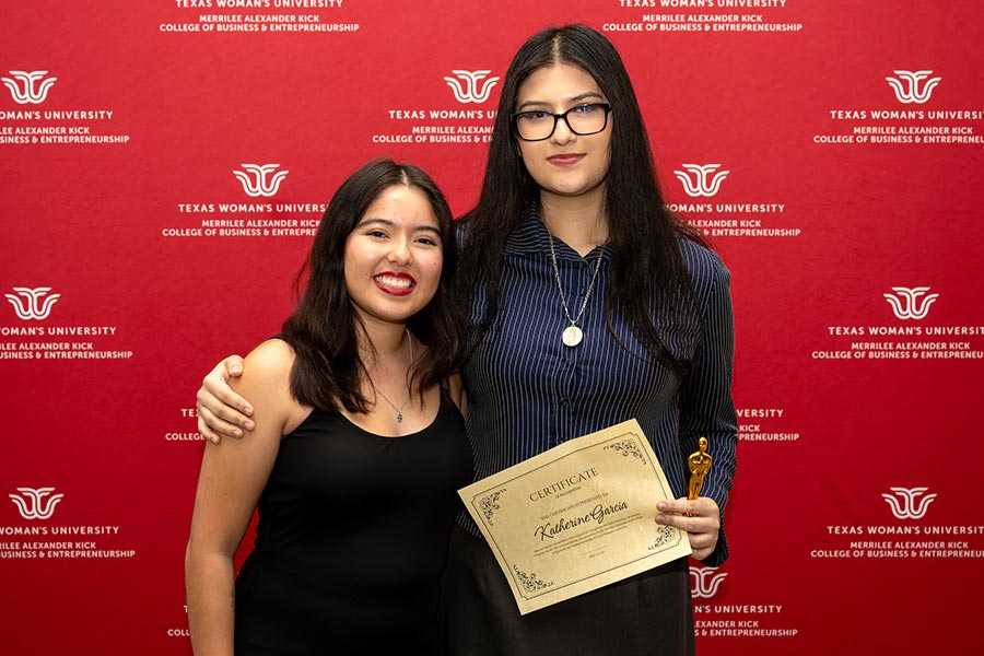 Katherine Garcia stands with her mentor in front of a TWU backdrop