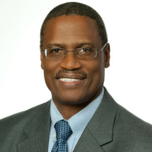 Black man, smiling and wearing a dark suit