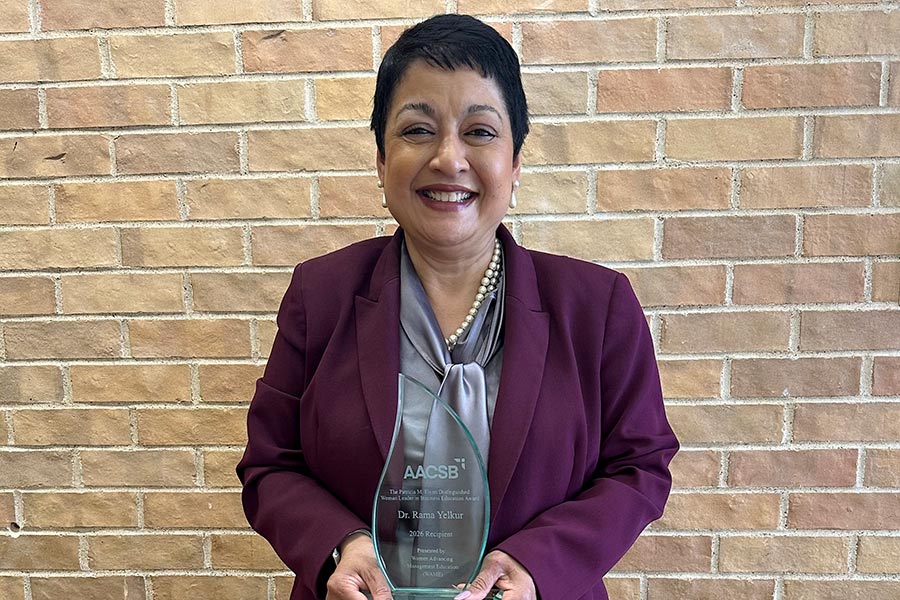 Dean Yelkur holding a glass plaque in front of a brick building