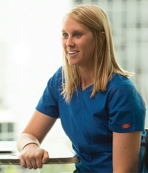 A Global Health student wearing scrubs and seated at a desk.