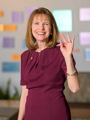 A portrait of Monica Christopher holding up the TWU hand sign.