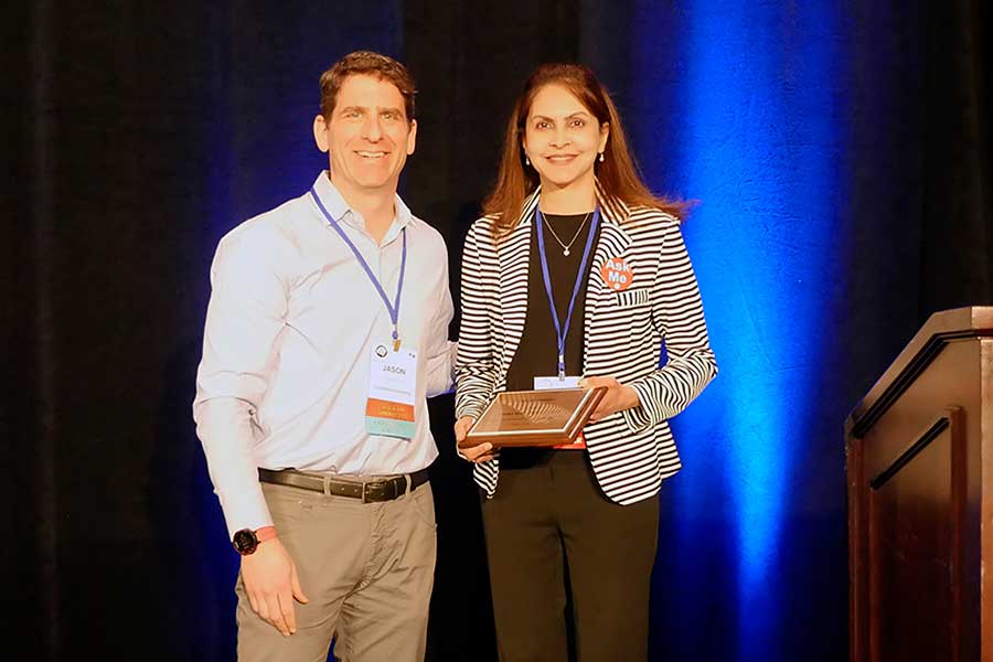 Texas Woman's professor stands with committee member, holding plaque