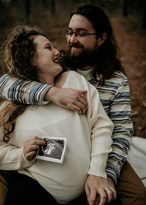 Katelynn Sparkman holds sonogram sitting with husband