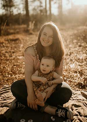 Katelynn Sparkman holds daughter in her lap outside among leaves