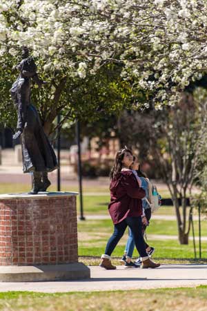 Students walk across campus near the She Gives Us Wings statue.