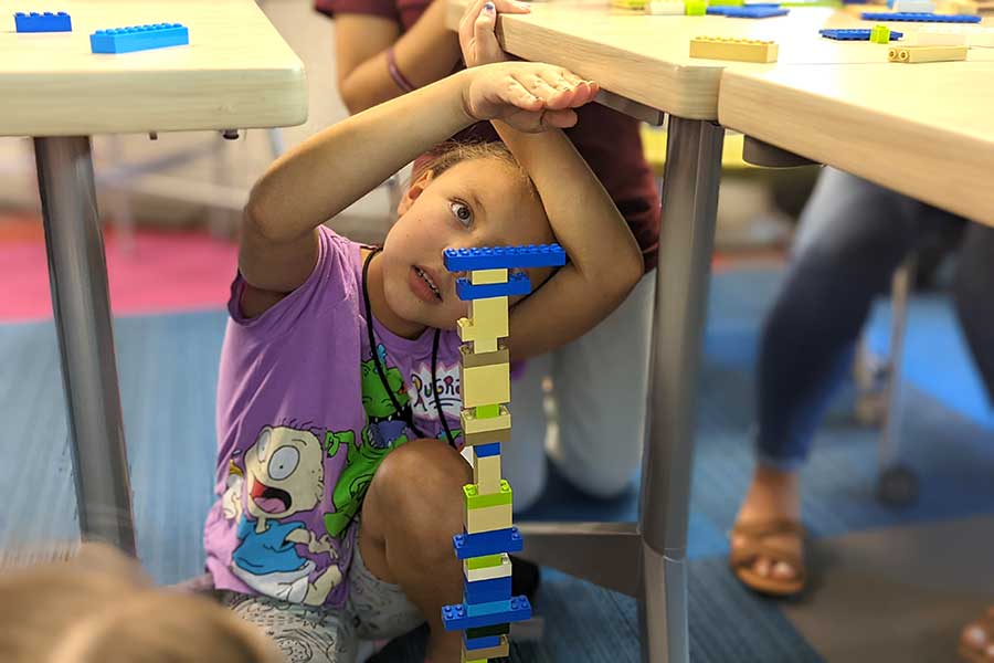 student works on stacking Legos while sitting on ground