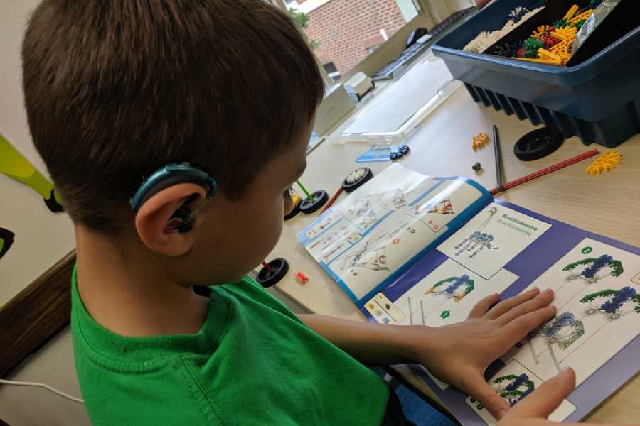 A DHH student reads the instructions for a K’Nex project