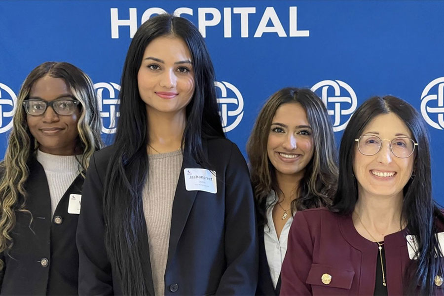 four MHA students stand in front of blue backdrop 