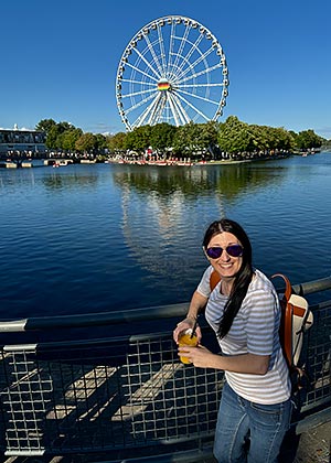 Tricia Whaley stands against railing with water and Ferris wheel in background