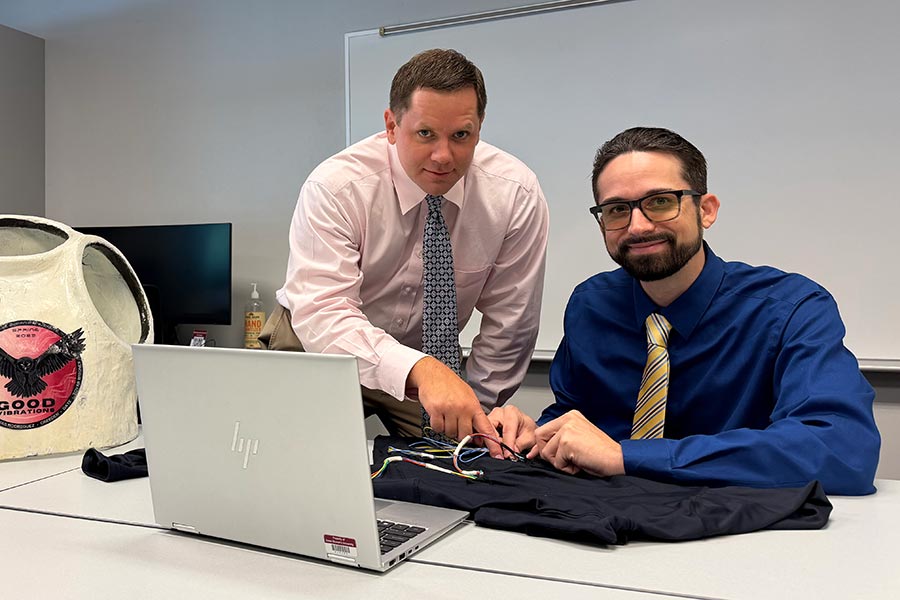 Rhett Rigby leans next to Hunter Alvis behind a computer and table