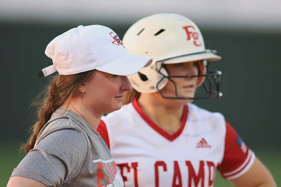 Haley Colwell in white hat and gray t-shirt stands next to softball player in batting helmet