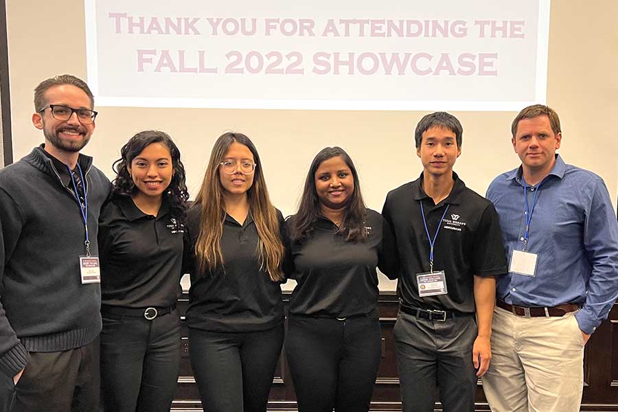 four students, a graduate advisor and a faculty advisor stand in a room