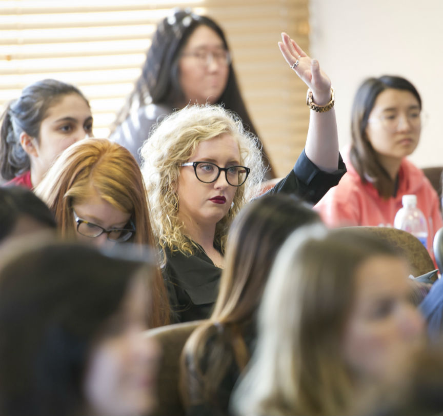 Student in classroom with hand raised