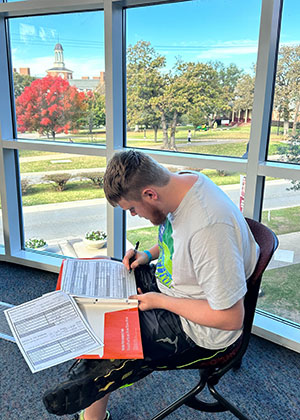 TWU and Transition Academy student sits at desk in Pioneer Hall in front of windows