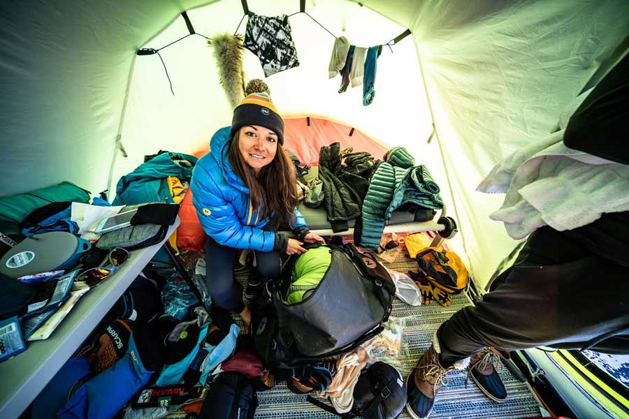 Roxanne Gonzales-Vogel packs a bag in a tent during a mountain climb.