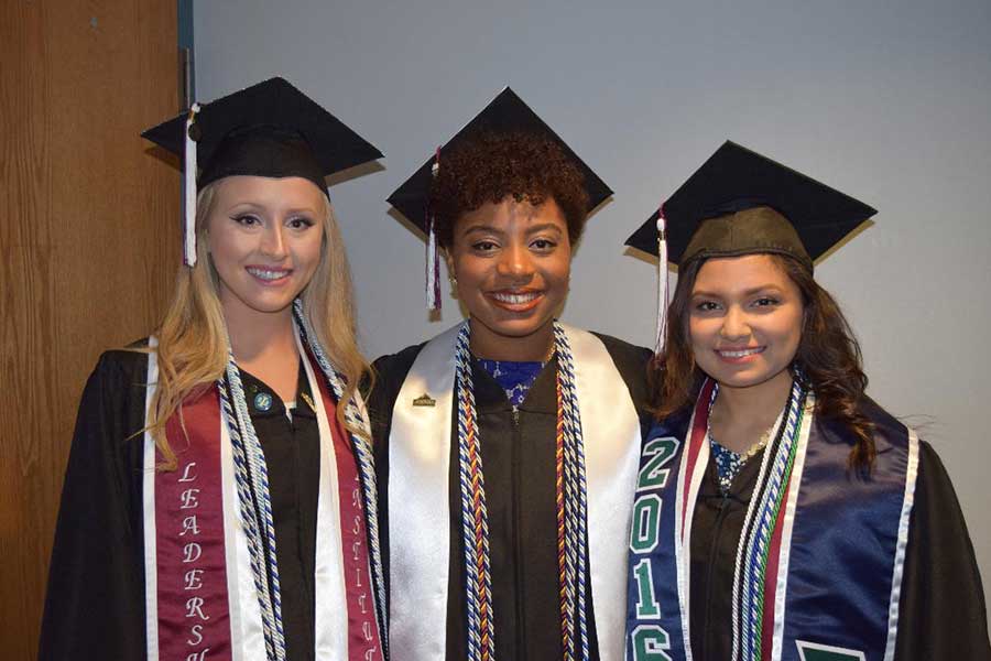 Three TWU Touchstone Honors graduates in their academic regalia.