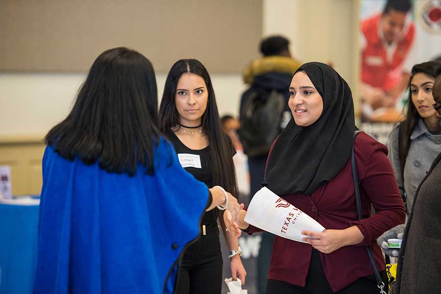 Two TWU students speak with an employer on campus.
