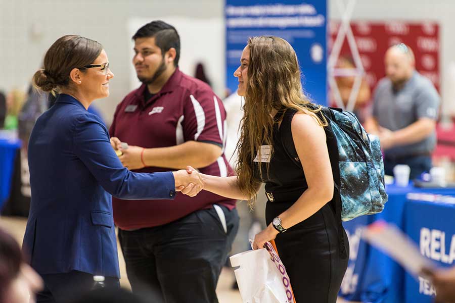 A TWU student meets an employer at a career fair.