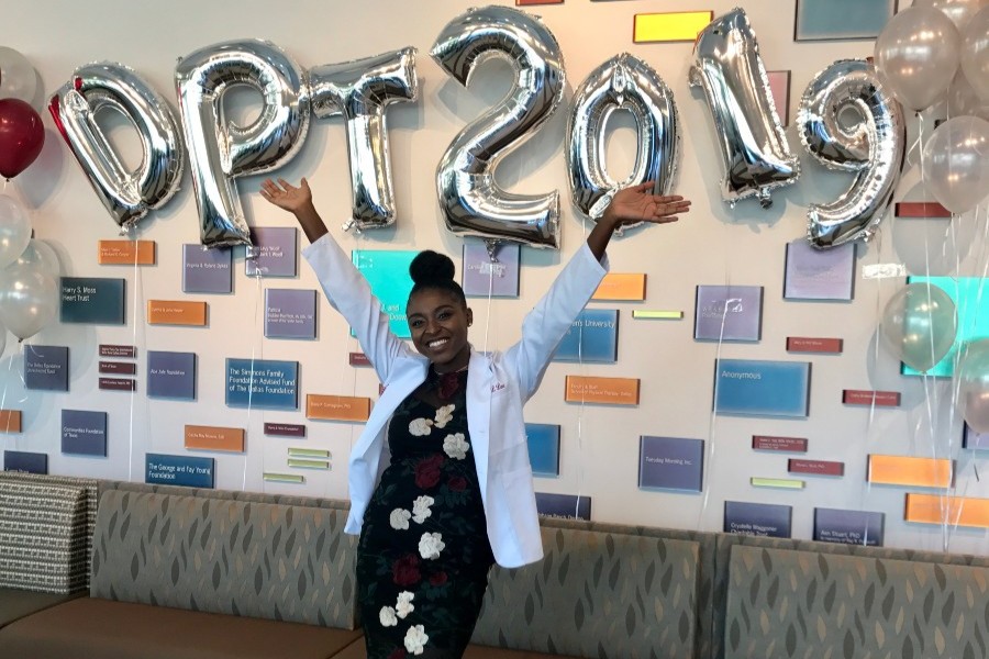 Adrian Lee smiling and posing in front of balloons that spell out "DPT 2019"