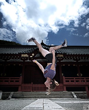 Luci Romberg mid-backflip in front of a Japanese temple.