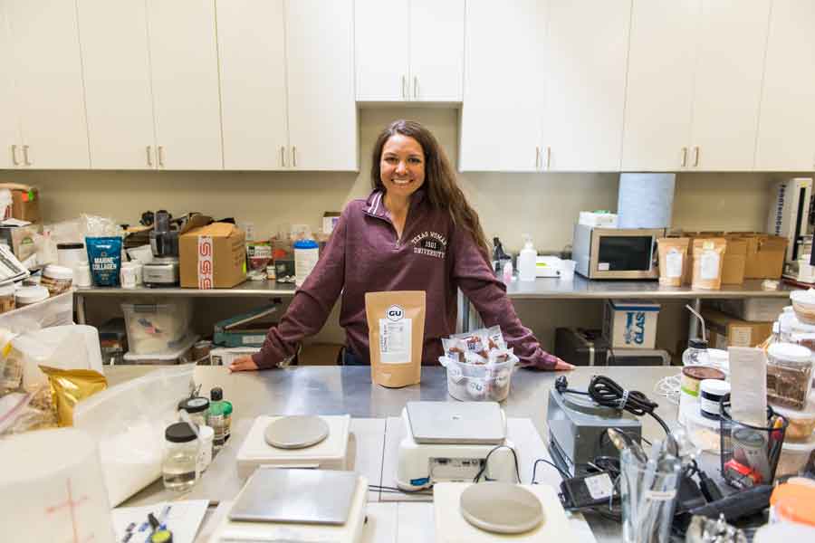 Roxanne Vogel in a GU Energy lab and surrounded by products.	
