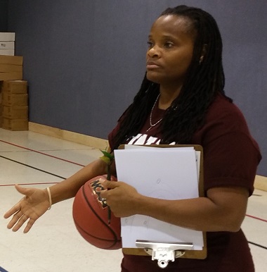 PE teacher holding white clipboard and a basketball.