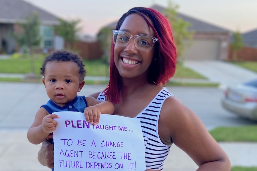 TWU PhD graduate Chloe Fields holds a sign that reads "PLEN taught me to be a change agent because the future depends on it."