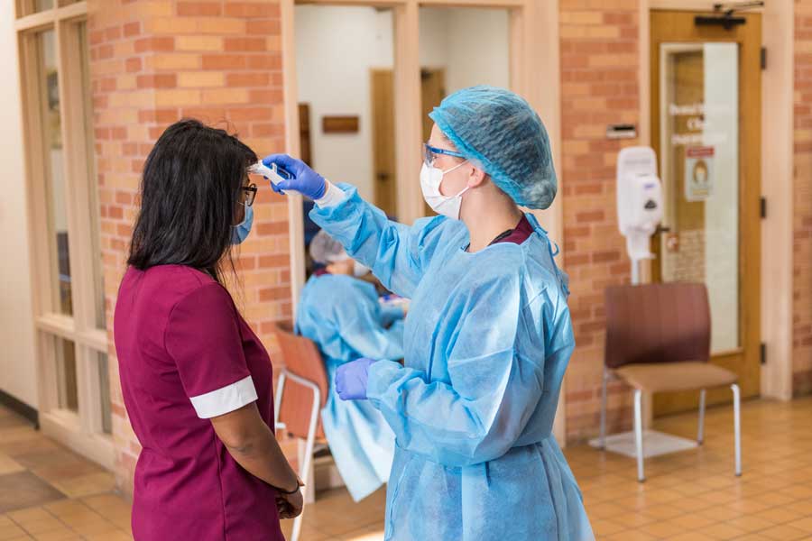 A TWU dental hygiene student takes the temperature of a patient before entering the clinic during the COVID-19 global pandemic.