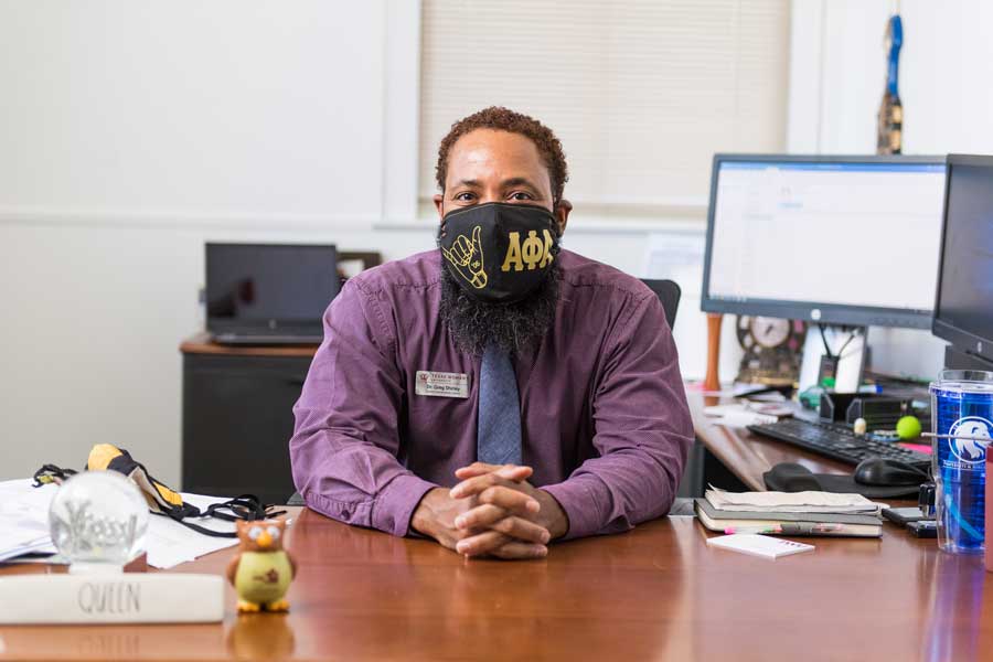 Dr. Greg Shirley wears a face mask at his desk on the TWU Denton campus.	