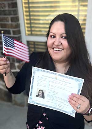 Patricia Aguirre, a graduate student, holds her citizenship paper and a small American flag in another hand