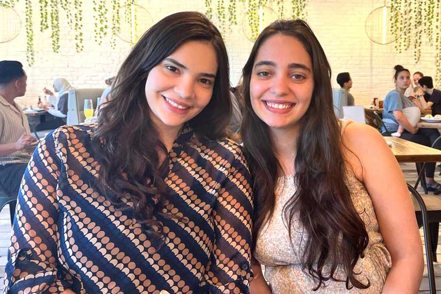 two women sit next to one another at restaurant 