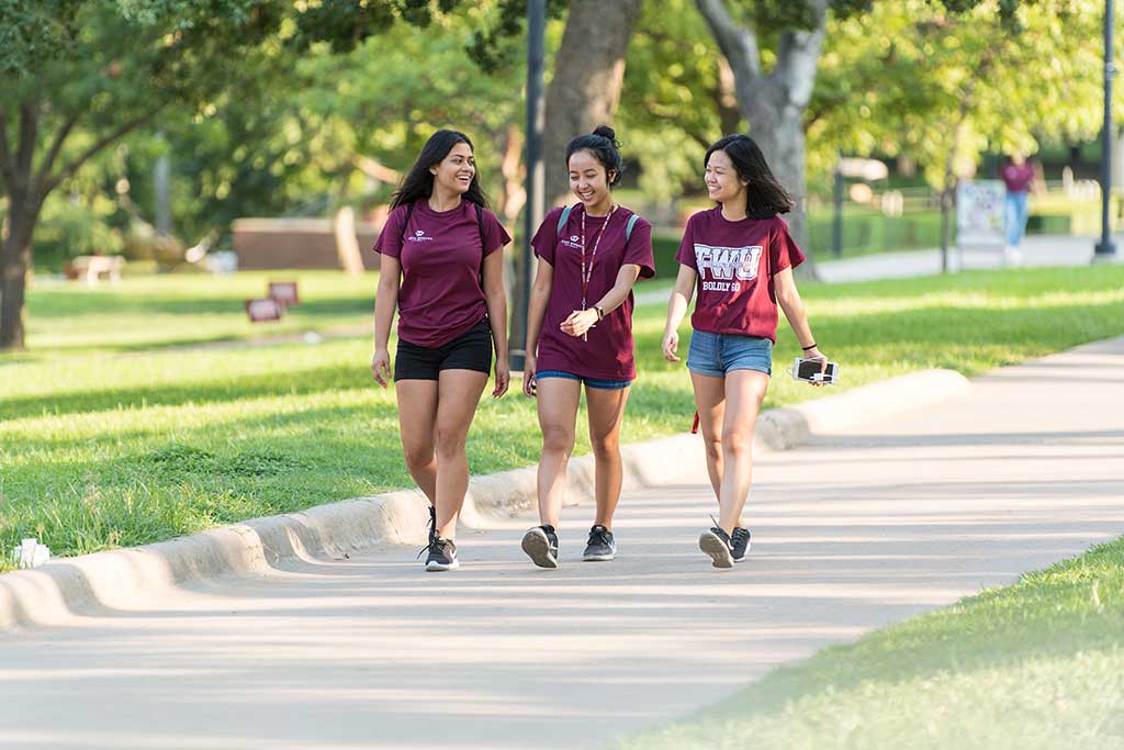 Three TWU students walking on campus on a sunny day.