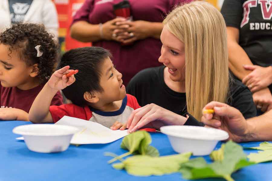 A child interacts with a TWU faculty member at an event.