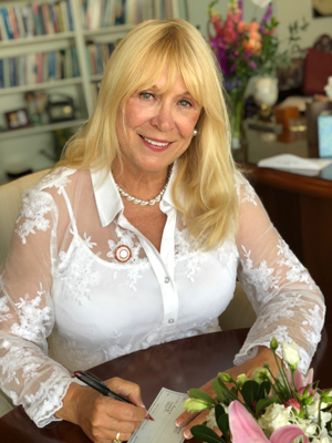 Mary L.A. Stanton seated at a table and signing a check.