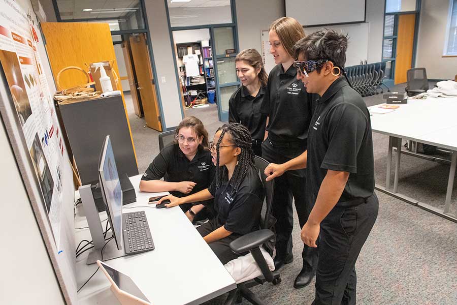 TWU students work around a computer.