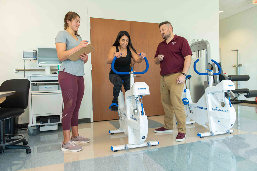 An athlete bikes while sports nutritionists oversee.